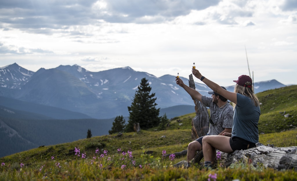 two people drinking whiskey shooters outside in the mountains